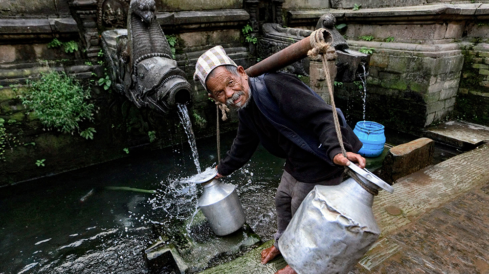 Asian man getting water from an outdoor tap.