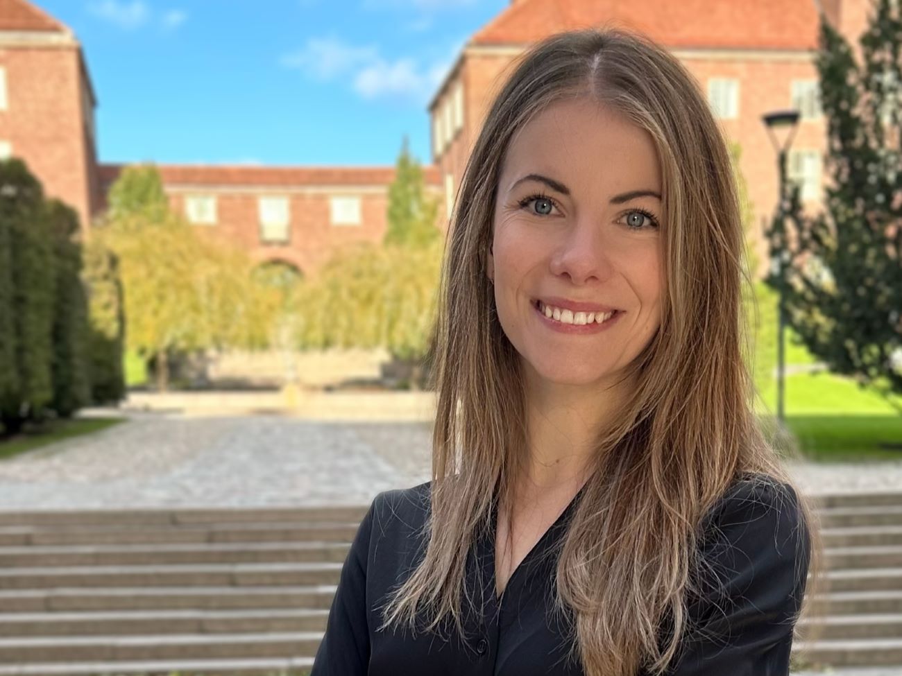 Girl in front of a KTH building, smiling