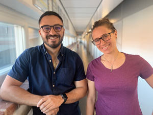 Man and woman in an office corridor smiling.