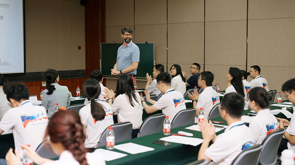 A European man teaching a group of Asian students.