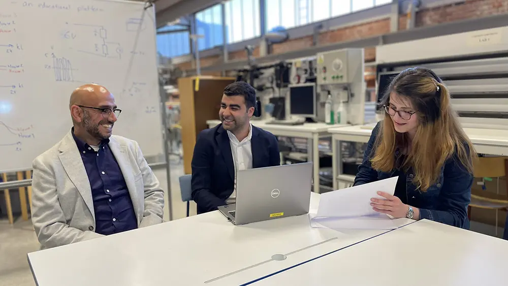 Three people at a table in an energy lab.